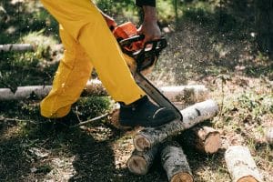 Uomo che usa la motosega seguendo le norme della Sicurezza sul lavoro nel giardinaggio